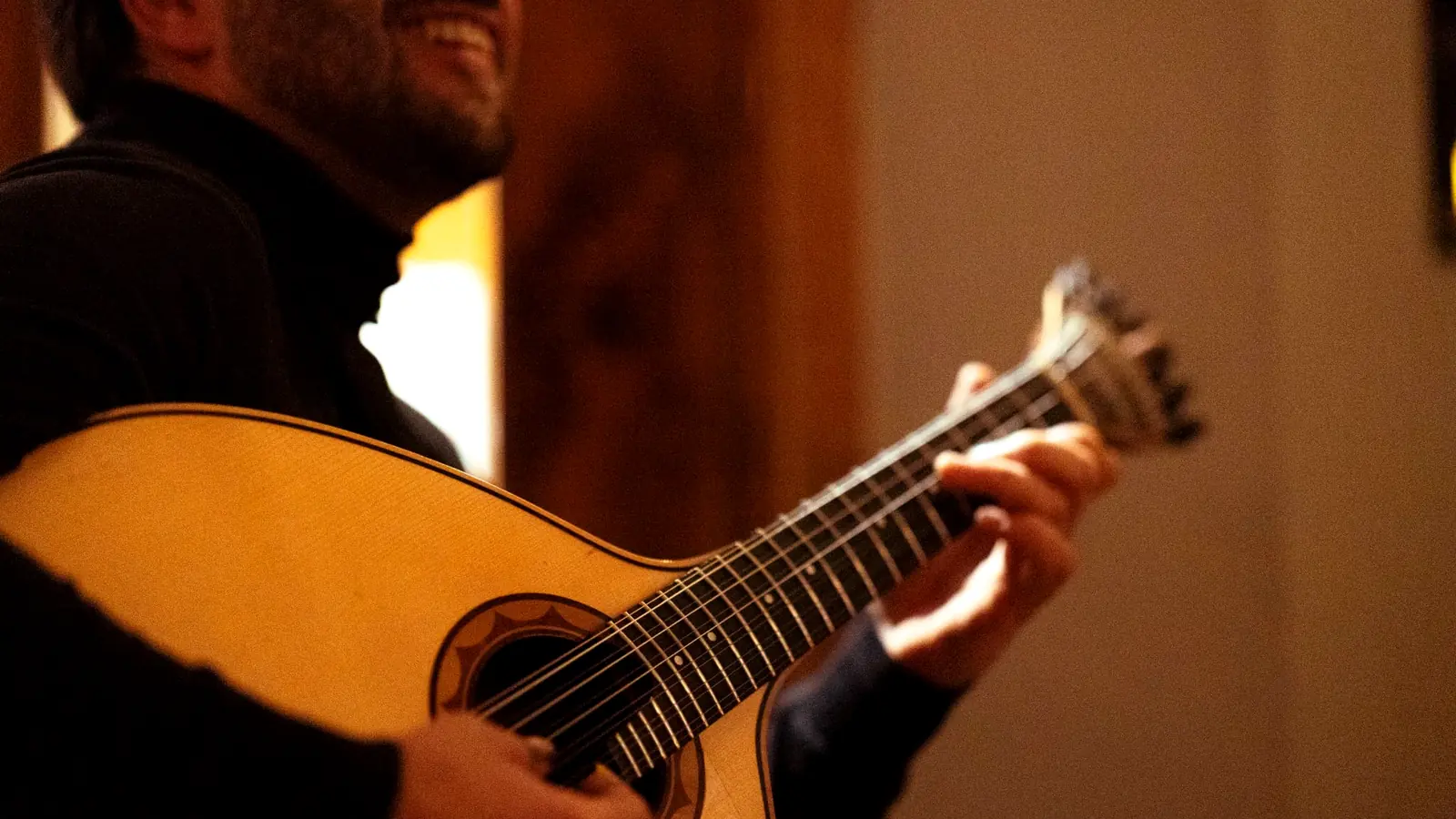 Ein Musiker lächelt, während er die portugiesische Gitarre spielt