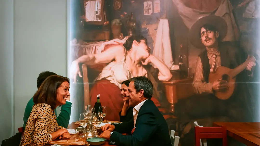 Ein Paar beim Abendessen im Fado ao Carmo, dahinter das Fado-Wandbild