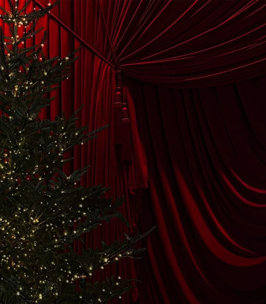Rideau de velours rouge avec un sapin de Noël illuminé