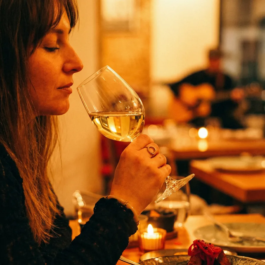Ein Glas Weißwein am Tisch, dahinter ein Gitarrist, an einem Fado-Abend im Fado ao Carmo
